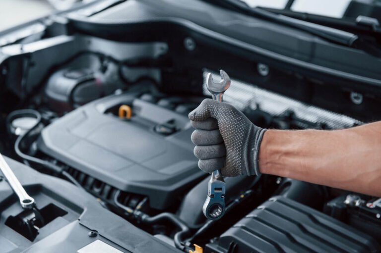 jumper cables connected to a car battery under an open hood in a Santa Cruz driveway